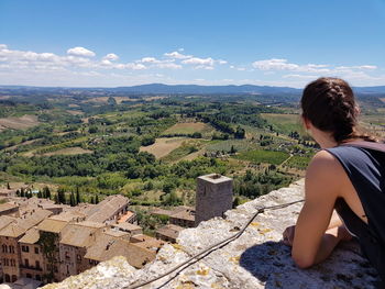 Rear view of woman sitting on landscape against sky