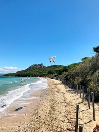 Scenic view of beach against clear blue sky