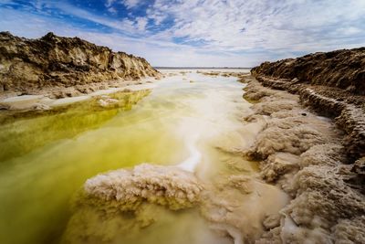 Scenic view of stream amidst rocks against sky