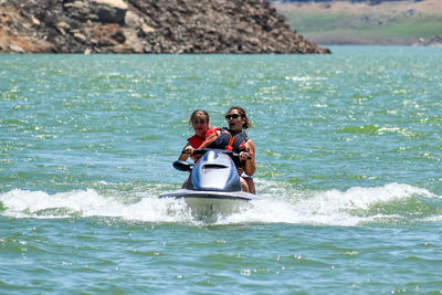 Woman with mother riding jet boat in sea 