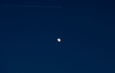 Low angle view of airplane flying against clear blue sky