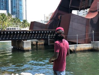 Woman standing by river against buildings in city