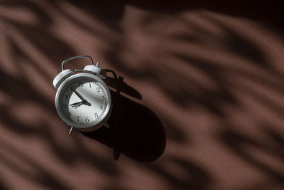 High angle view of clock on brown background