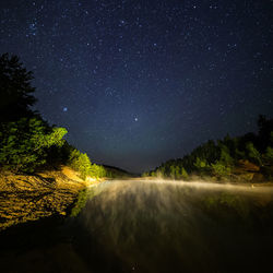 Small lake under stars at night with foggy vapour at summer.