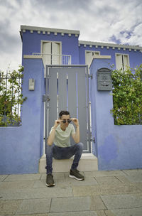 Portrait of young man sitting on building