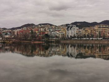 Reflection of buildings in lake against sky in city