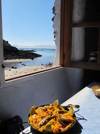 Close-up of a pot of paella with seascape in background