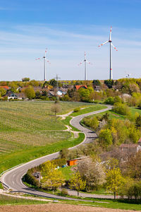 A striking road leads between vineyards to a settlement surrounded by wind turbines