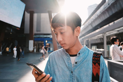 Close-up of man using phone while standing in city