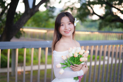 Portrait of young woman standing against trees