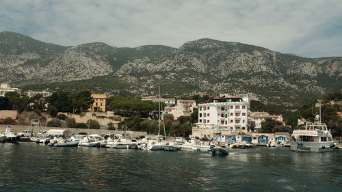 Sailboats moored in sea against buildings in city