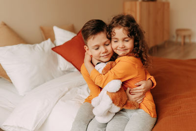 Happy children brother and sister in pajamas lying on the bed in interior of the bedroom of  house