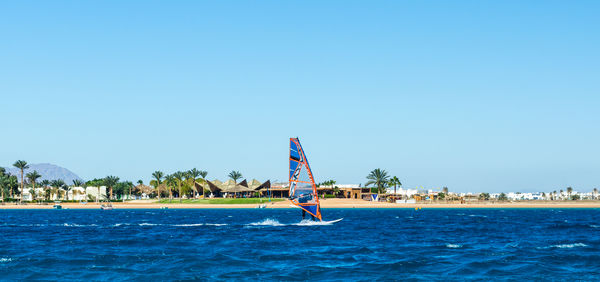 Man windsurfing in sea against clear sky