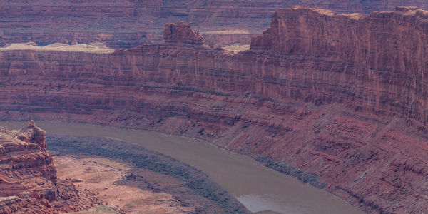 Rugged red sandstone rock formations tower above the eroded landscape with river