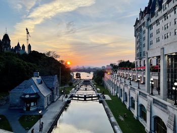 Canal amidst buildings against sky during sunset