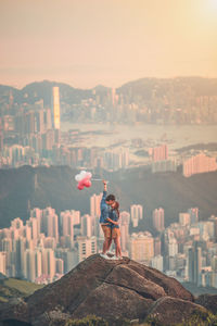 Man standing on rock against buildings in city