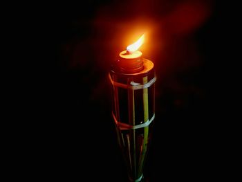 Close-up of illuminated candle over black background