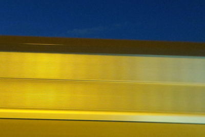 Close-up of yellow wall against blue sky