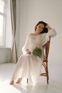 Young woman sitting on bed at home