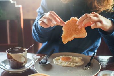 Midsection of woman holding toasted bread at home