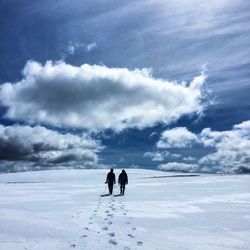 Men on snowcapped landscape against sky