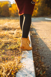 Happy fall, hello autumn, fall season. female legs in yellow boots walking along the curb with fall
