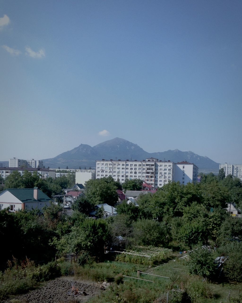 building exterior, architecture, built structure, tree, clear sky, mountain, copy space, blue, house, residential structure, residential building, sky, day, landscape, residential district, town, nature, mountain range, outdoors, growth