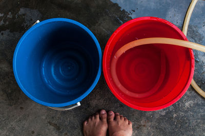 Low section of person standing by buckets on floor