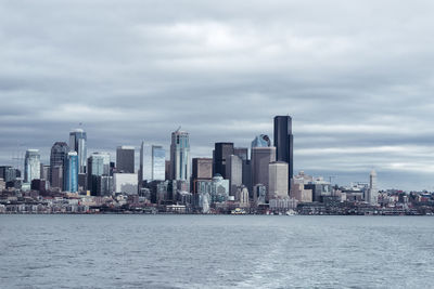 City at waterfront against cloudy sky