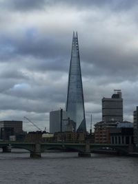 Buildings in city against cloudy sky