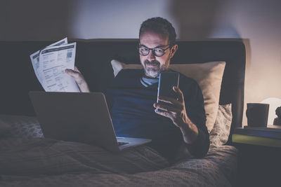 Man works with laptop lying on bed. male home working remote office sitting in bedroom use devices