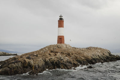 Lighthouse by sea against sky