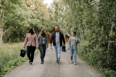 Smiling daughters with father and mother walking on footpath during vacations