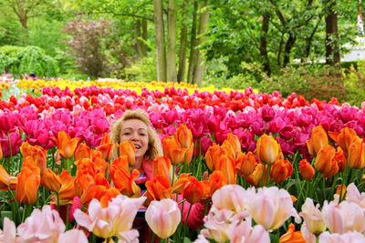 Portrait of happy woman sitting amidst multi colored tulips in garden