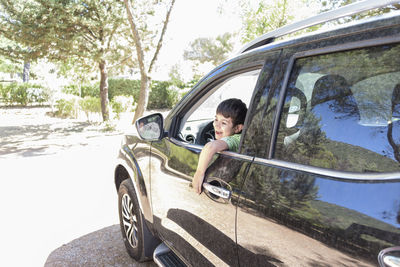 Laughing boy looking out of car window. happy child in the back seat of the car enjoying the view 