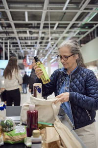 Woman putting groceries in bag at checkout counter