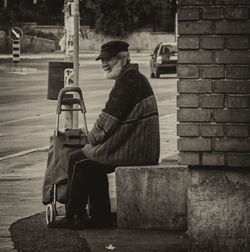 Rear view of man sitting on wall