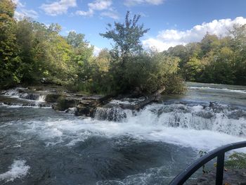 Scenic view of waterfall in forest against sky