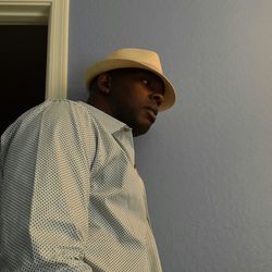 Low angle view of man wearing hat by wall at home
