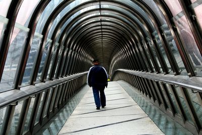 Rear view full length of man walking in covered footbridge