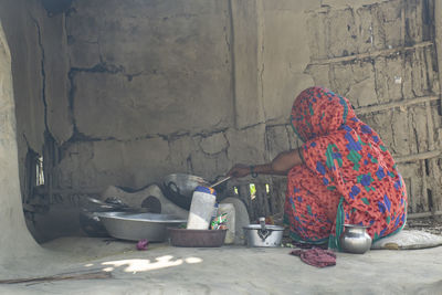 Rear view of woman working against wall