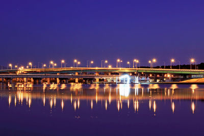 Illuminated bridge over river against sky at night