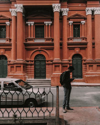 Rear view of man standing by railing against building