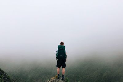 Rear view of man standing on landscape against sky