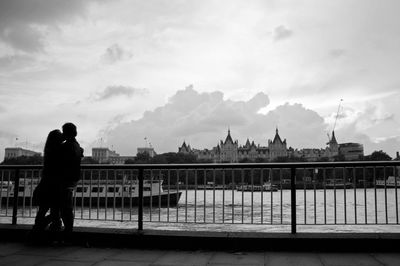 Silhouette of man with river against cloudy sky