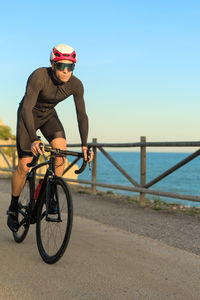 Rear view of man riding bicycle on beach against clear sky
