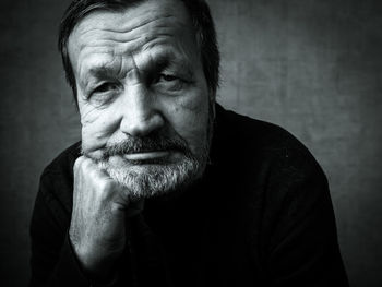 Close-up portrait of senior man against wall