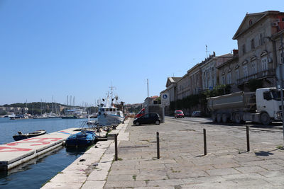 Sailboats moored at harbor against clear blue sky