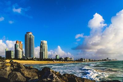 City at waterfront against cloudy sky