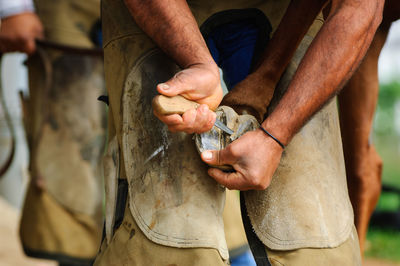 Midsection of man adjusting horse shoe